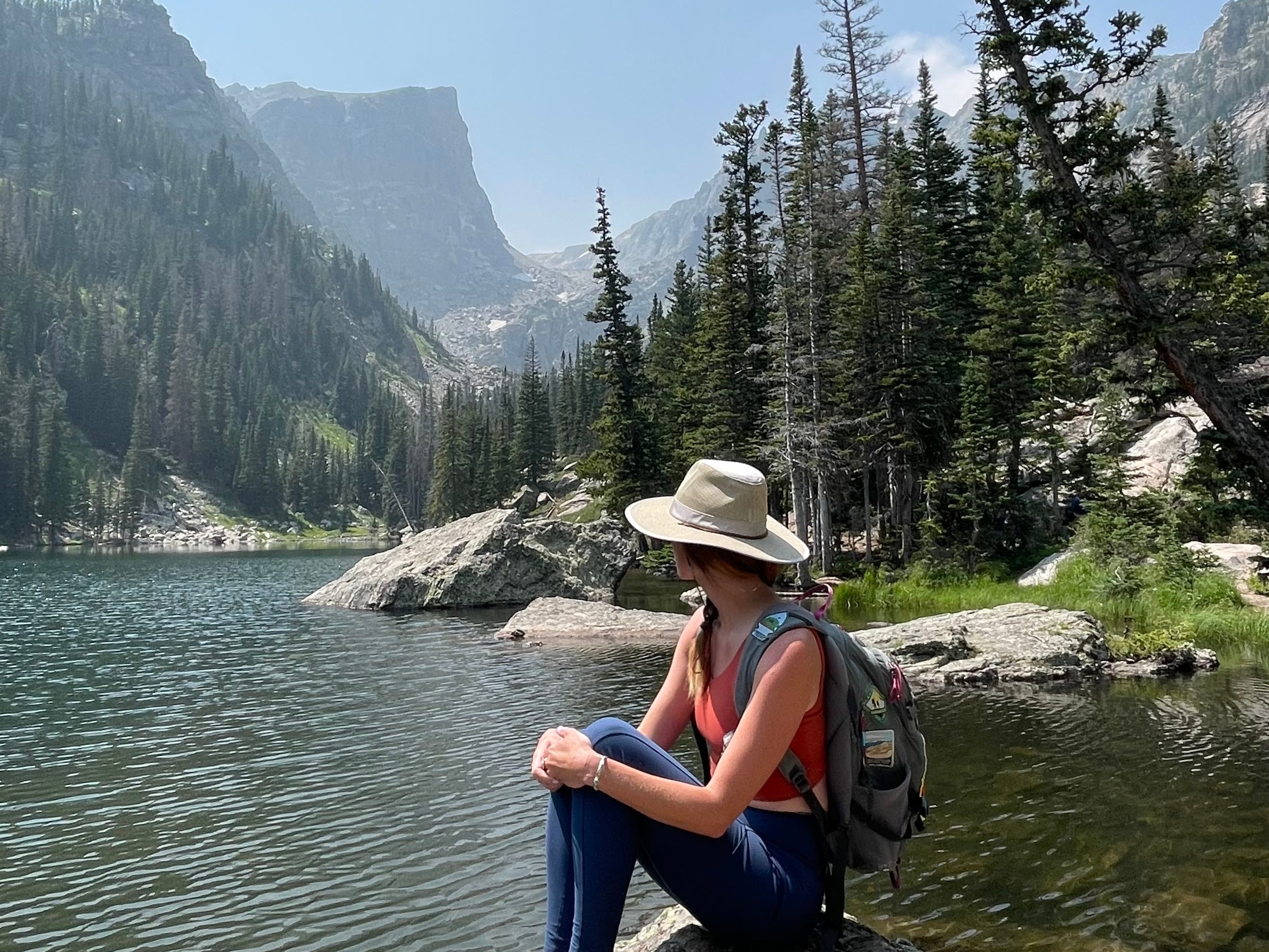 Emily sits on a rock overlooking a body of water at Rocky Mountain National Park.
