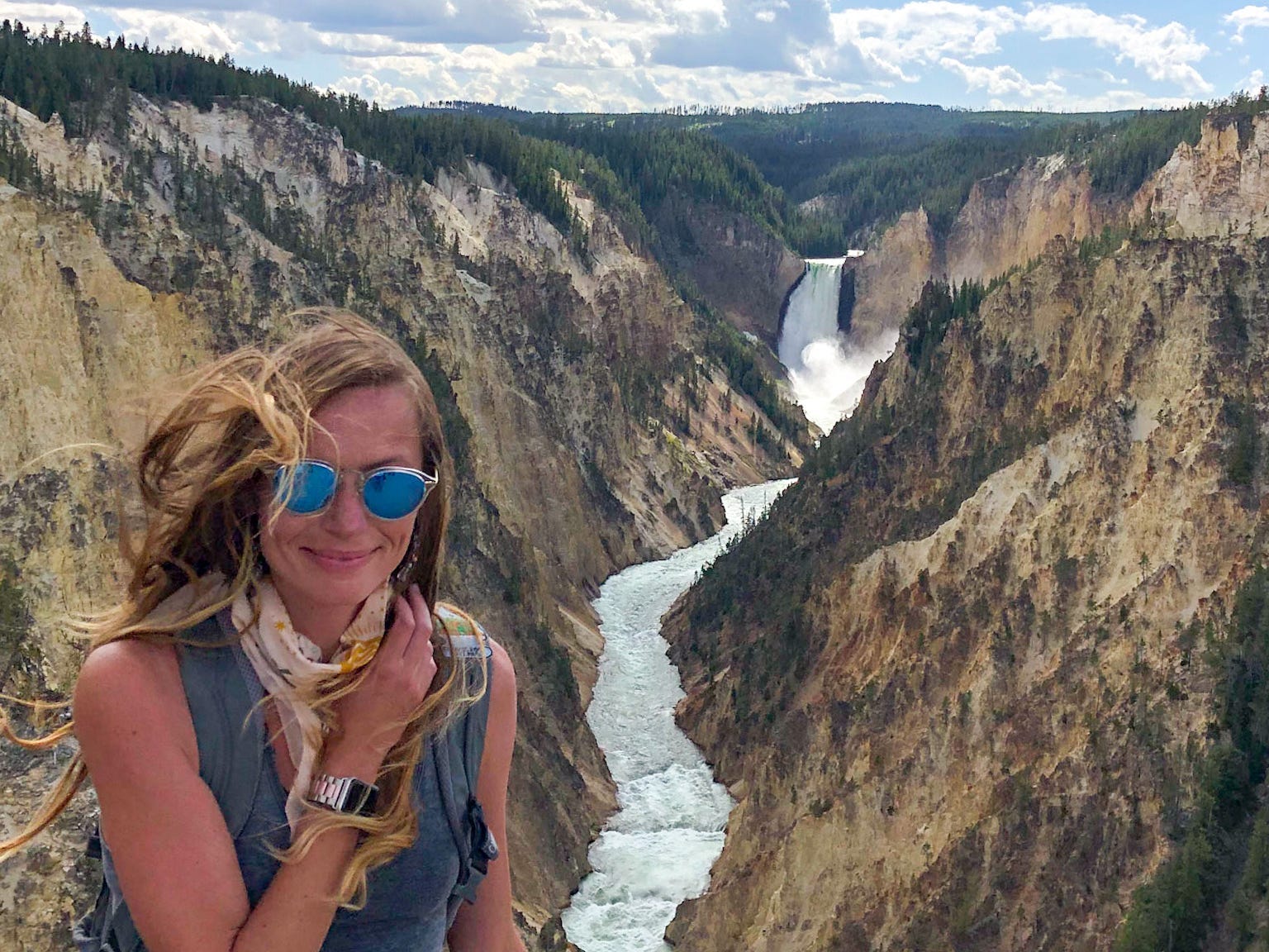 Emily poses with her hand resting on a rock and the Grand Canyon of the Yellowstone behind her.