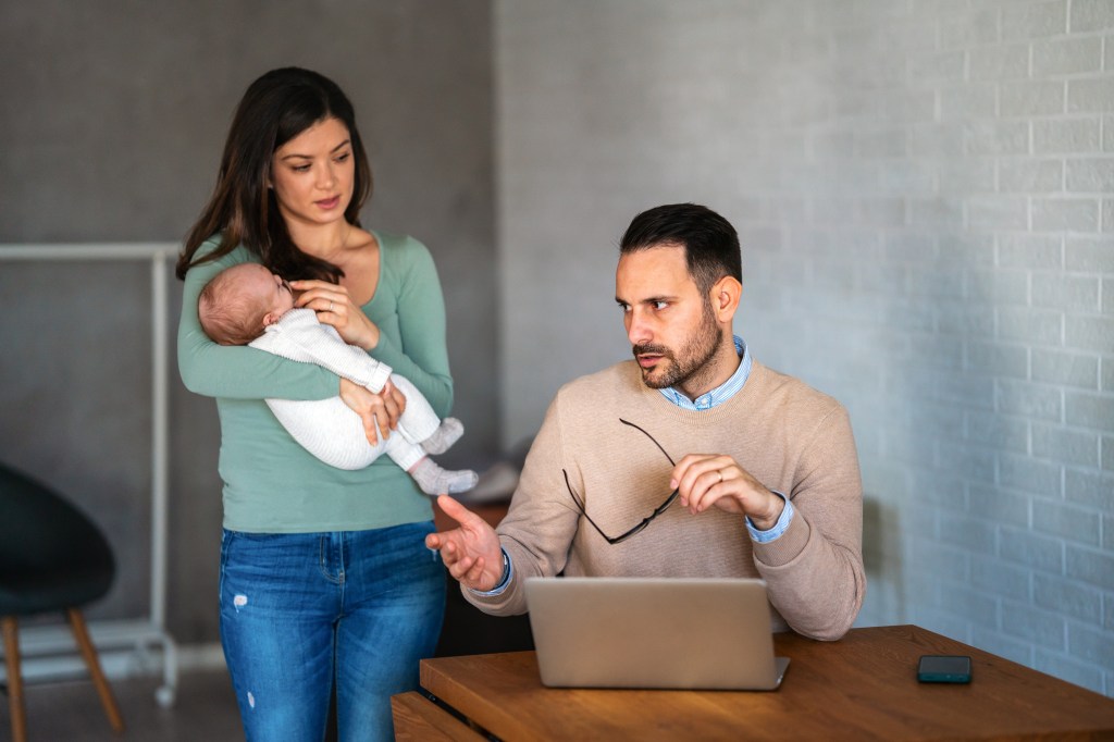 Stressed couple with baby arguing at home.