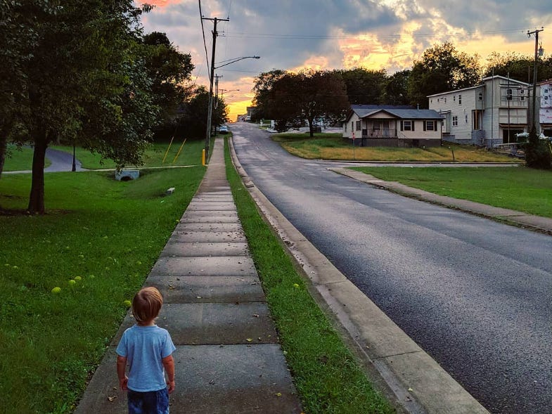 Kid walking down empty street in Nashville during sunset