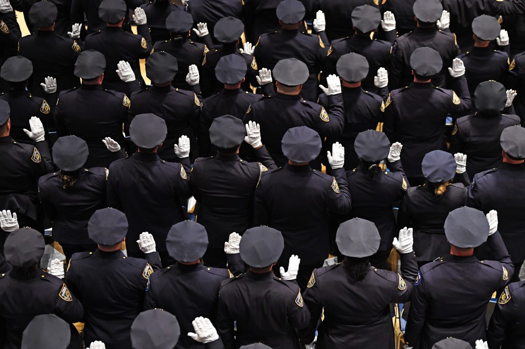 NYPD officers raising their right hands during a promotion ceremony.