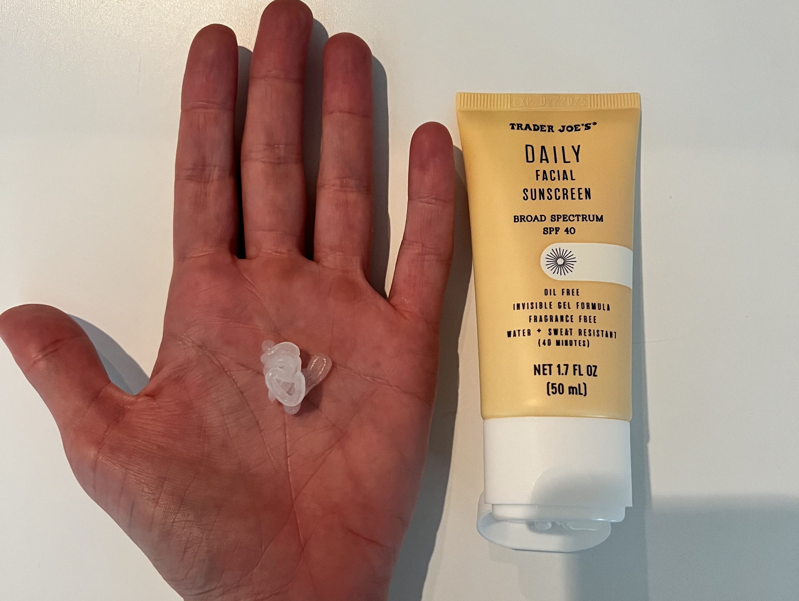 Author holding out hand with a dollop of sunscreen on it, next to a bottle of Trader Joe's sunscreen.