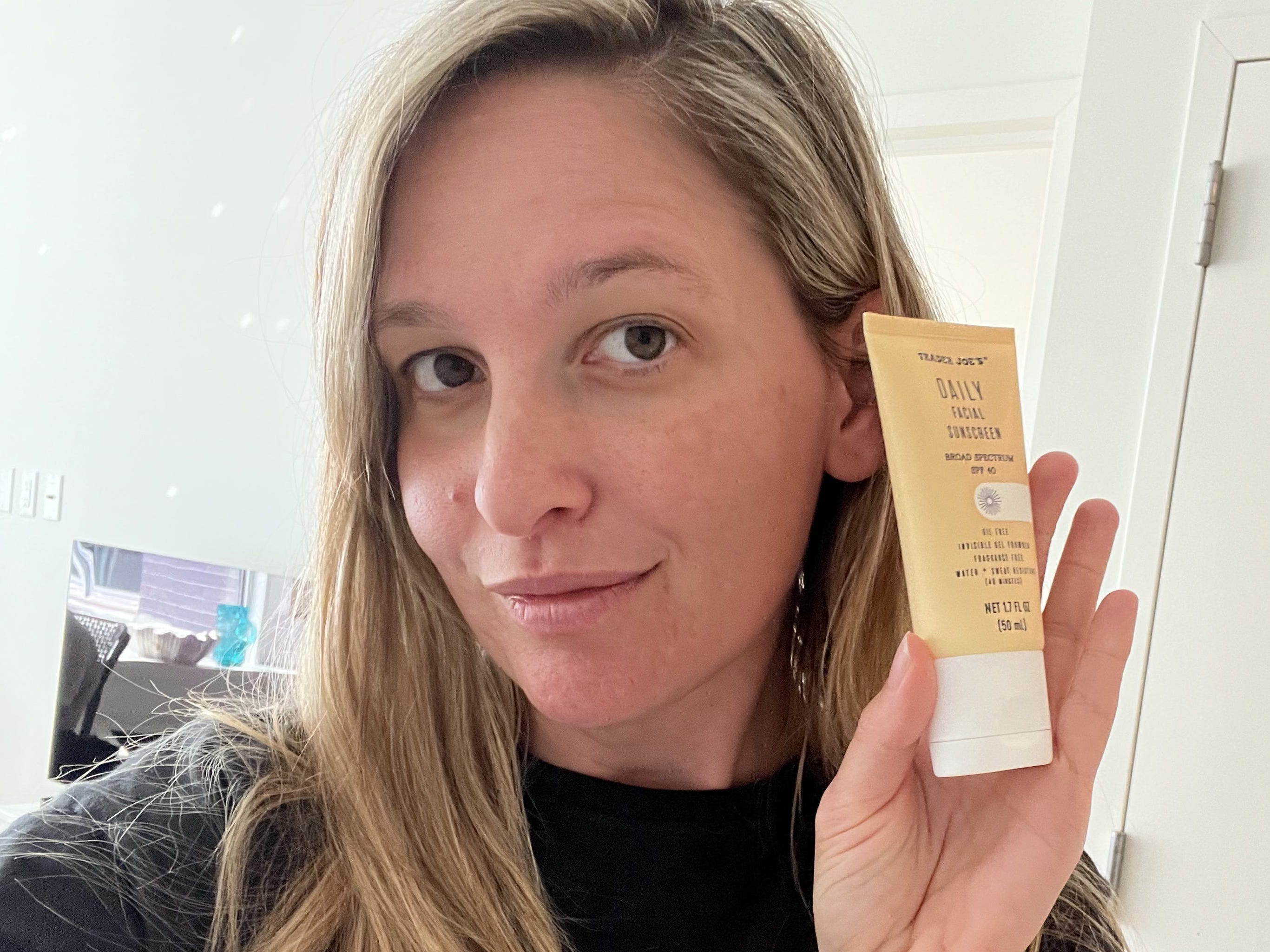 Author holding up Trader Joe's sunscreen in selfie.