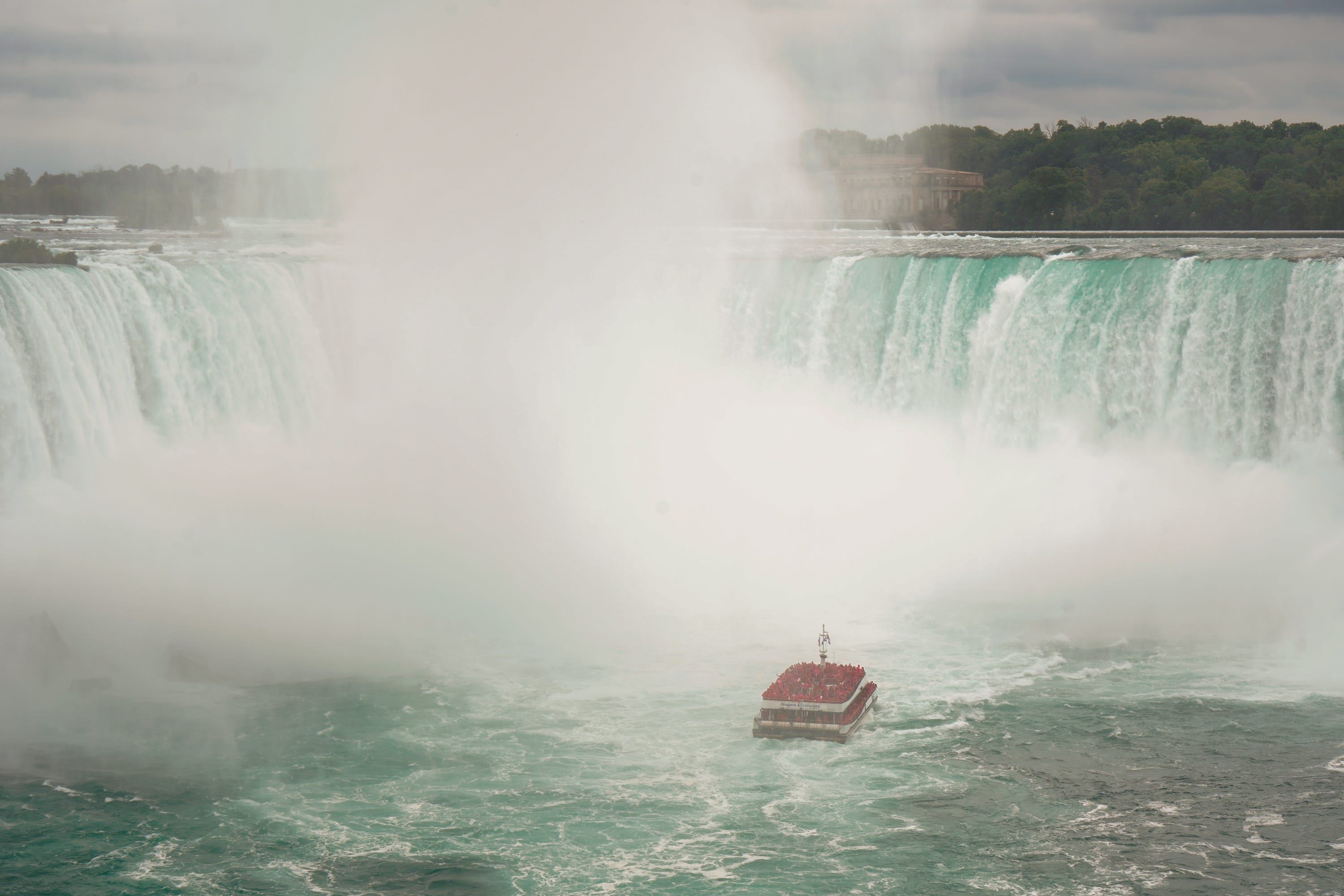 A boat approaches Horseshoe Falls at Niagara Falls on a cloudy day