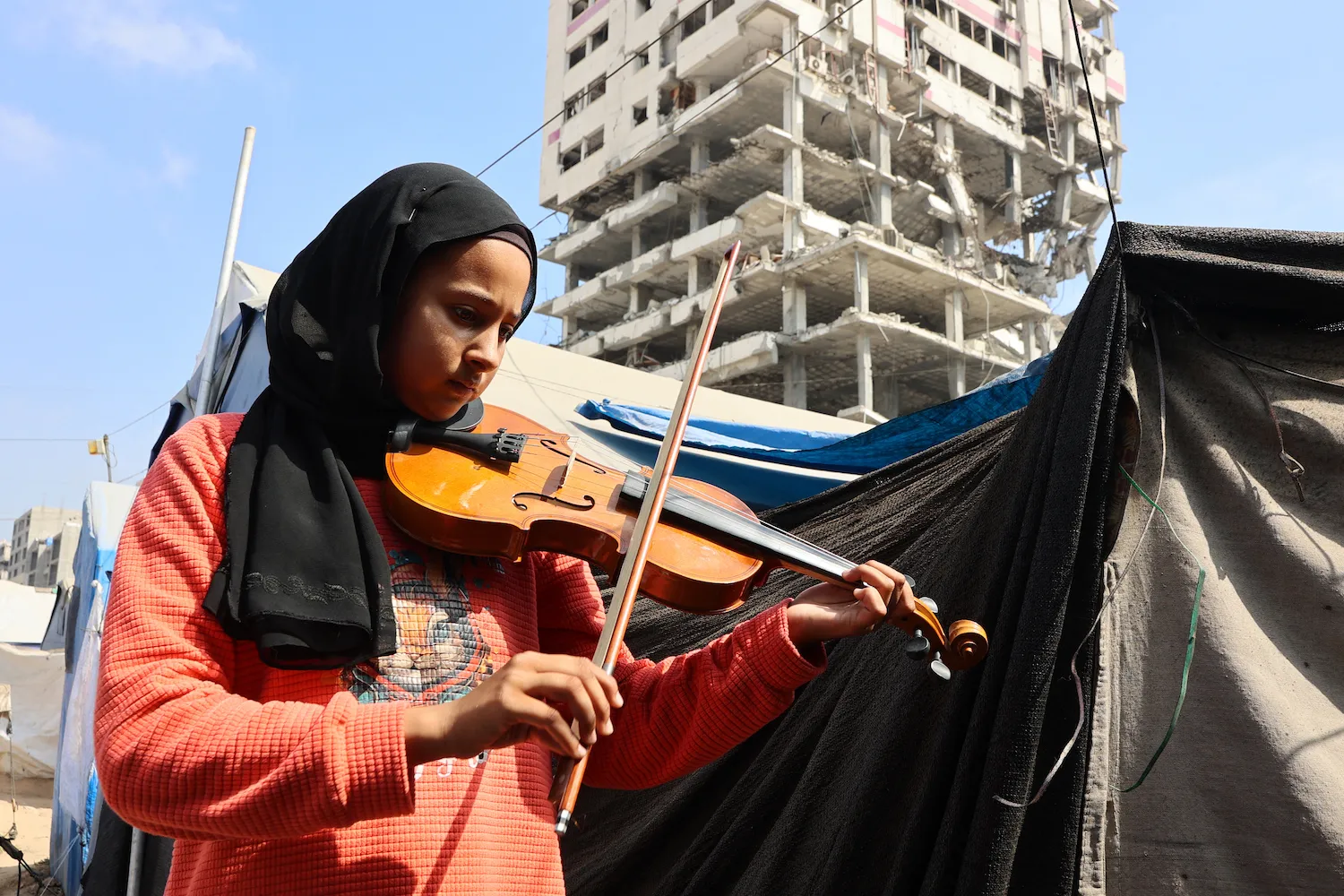 A student plays the violin during a music class in a camp for displaced Palestinians in the northern Rimal neighborhood of Gaza City on July 10.