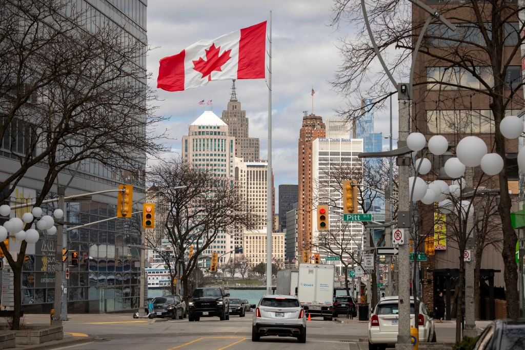 Canadian flag flying in Windsor, Canada, with the Detroit skyline in the background.
