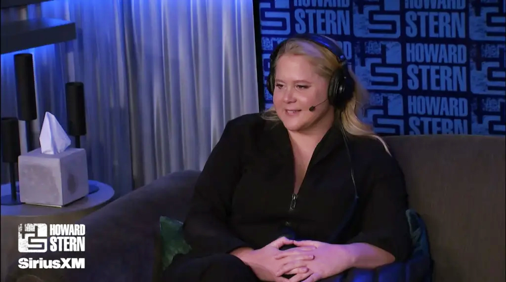 Amy Schumer sits in a chair while giving a radio interview. 