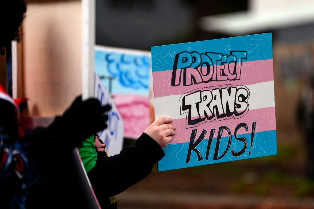 A protester holds a pro-transgender kids right outside of Seattle Children's Hospital after gender-affirming surgeries for minors were postponed on Feb. 9, 2025.