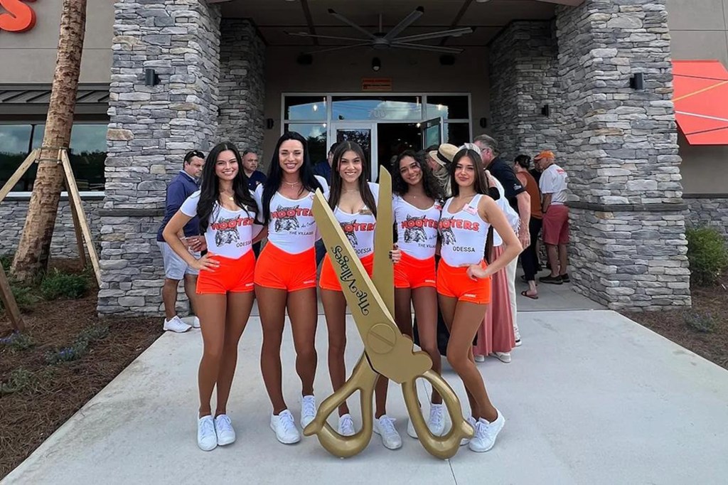 Hooters waitresses pose for a photograph with a giant pair of scissors outside the new restaurant.