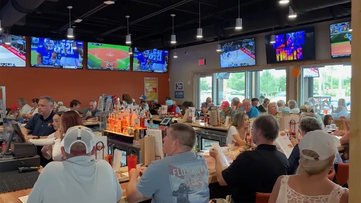 Crowded bar and restaurant interior with multiple TVs showing sporting events.