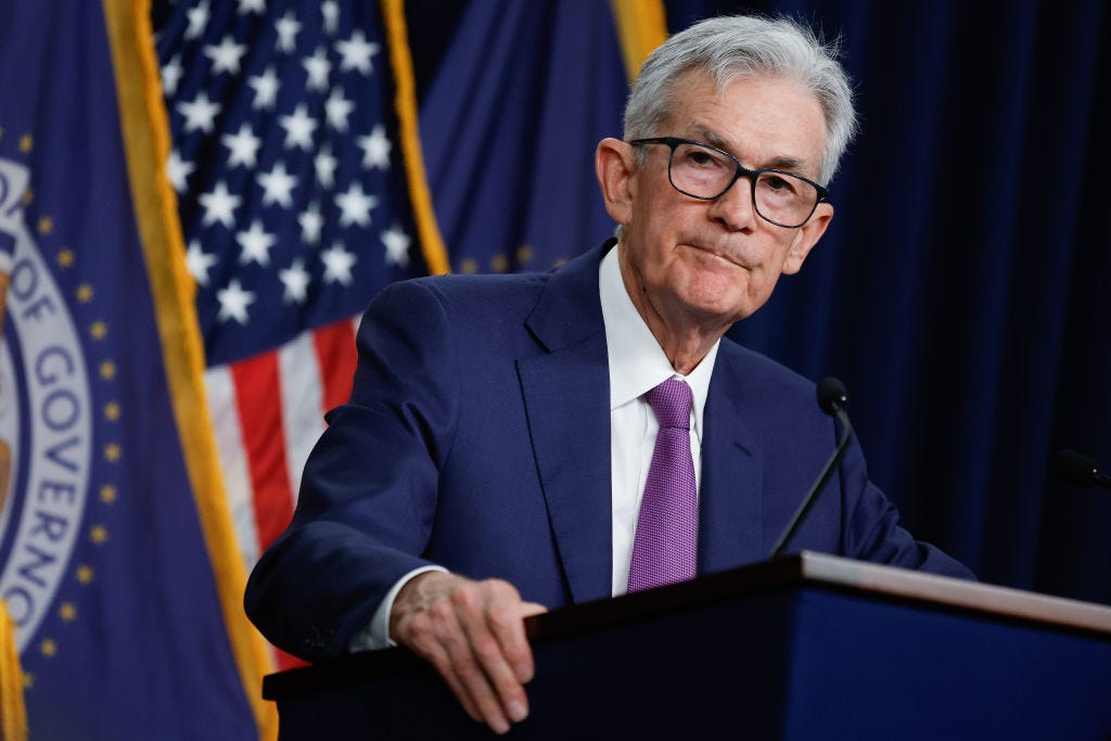Jerome Powell speaking from a podium, wearing a suit and tie.