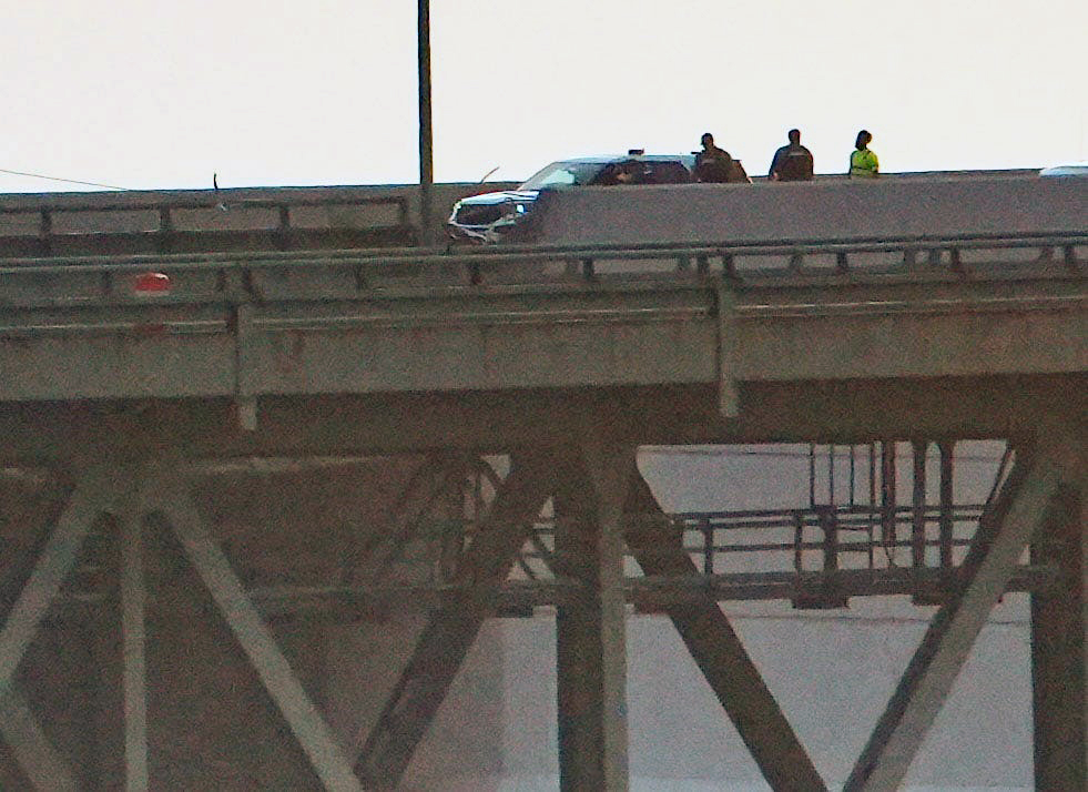 Emergency personnel on a bridge after a vehicle accident.