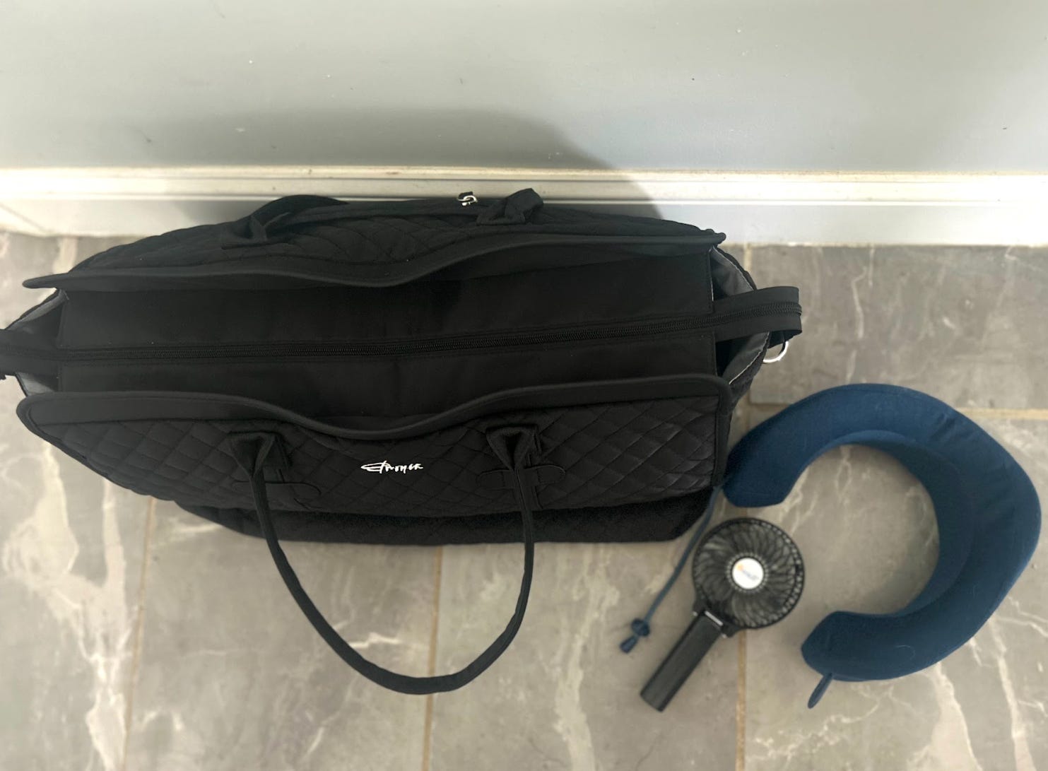 The writer's carry-on, neck pillow, and portable fan that she brought on a flight to London.