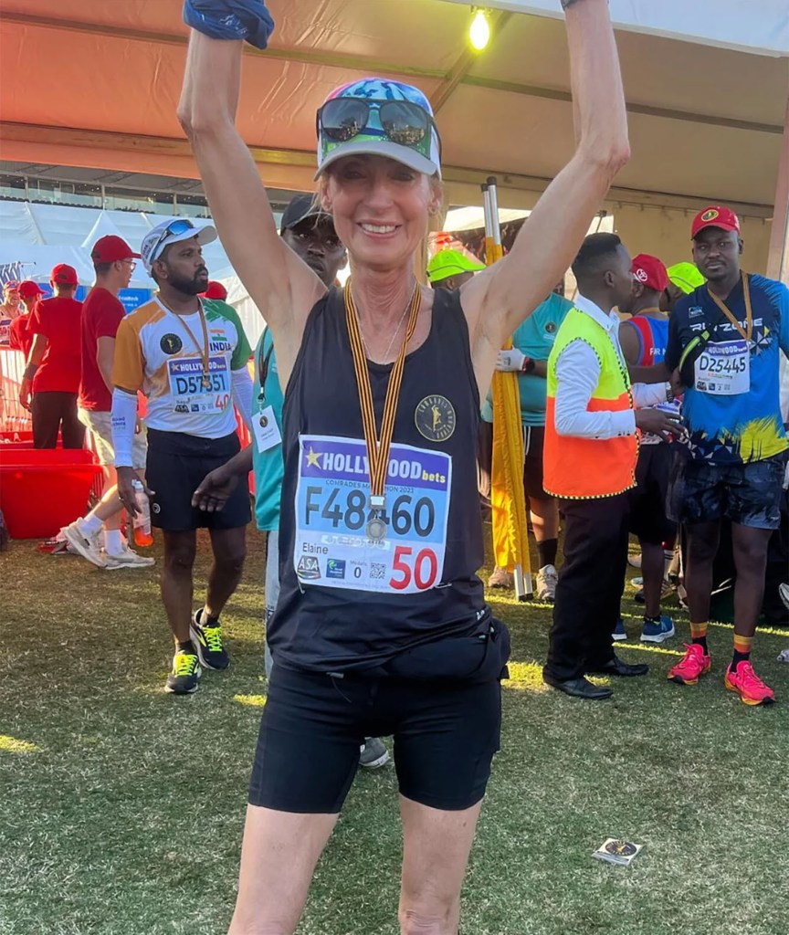 A female ultrarunner with arms raised victoriously, wearing a bib numbered F48460.