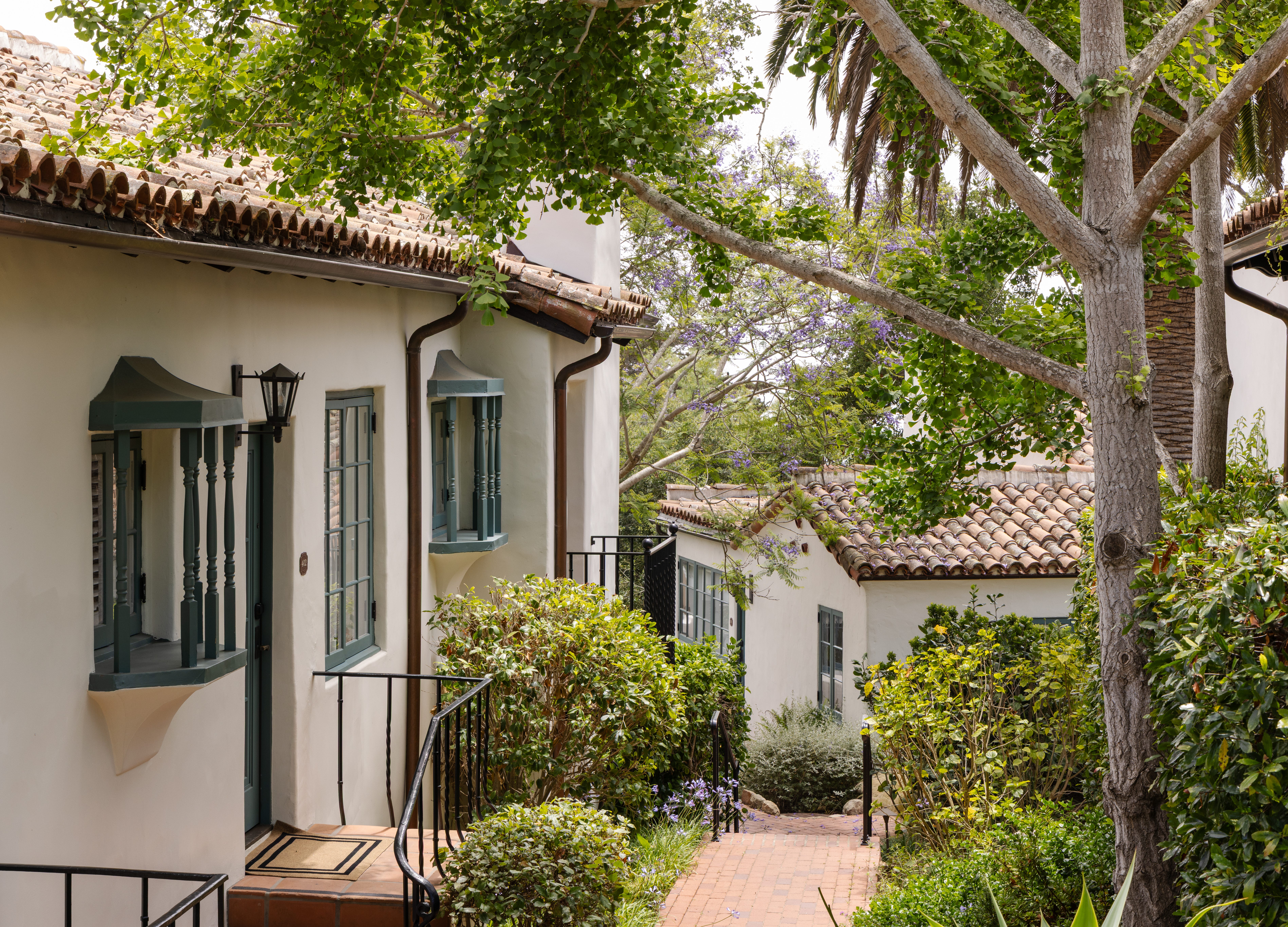 An exterior view of a hotel path between white buildings with shingled roofs.