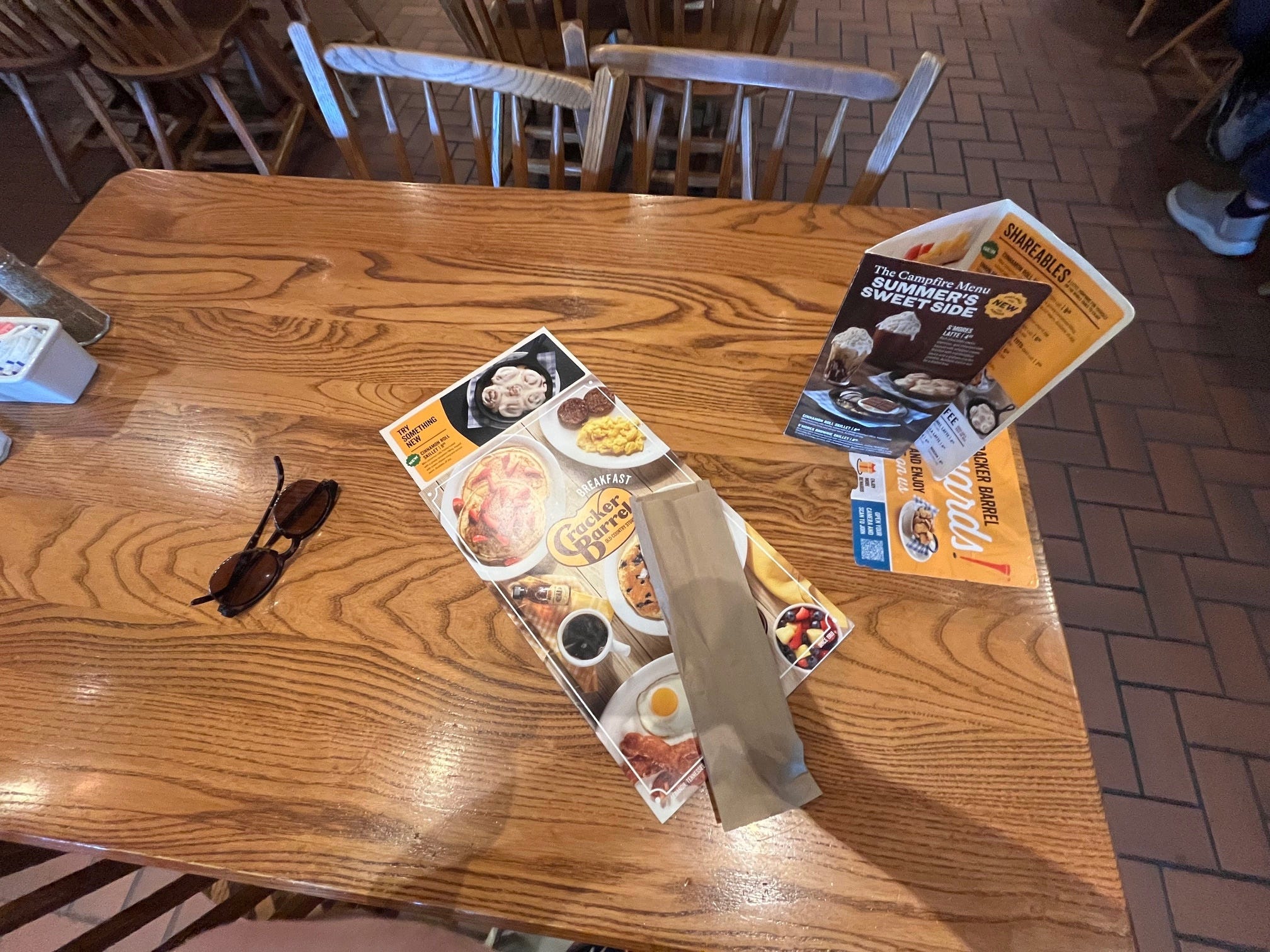 A menu and a pair of sunglasses sit on a table at a Cracker Barrel restaurant.