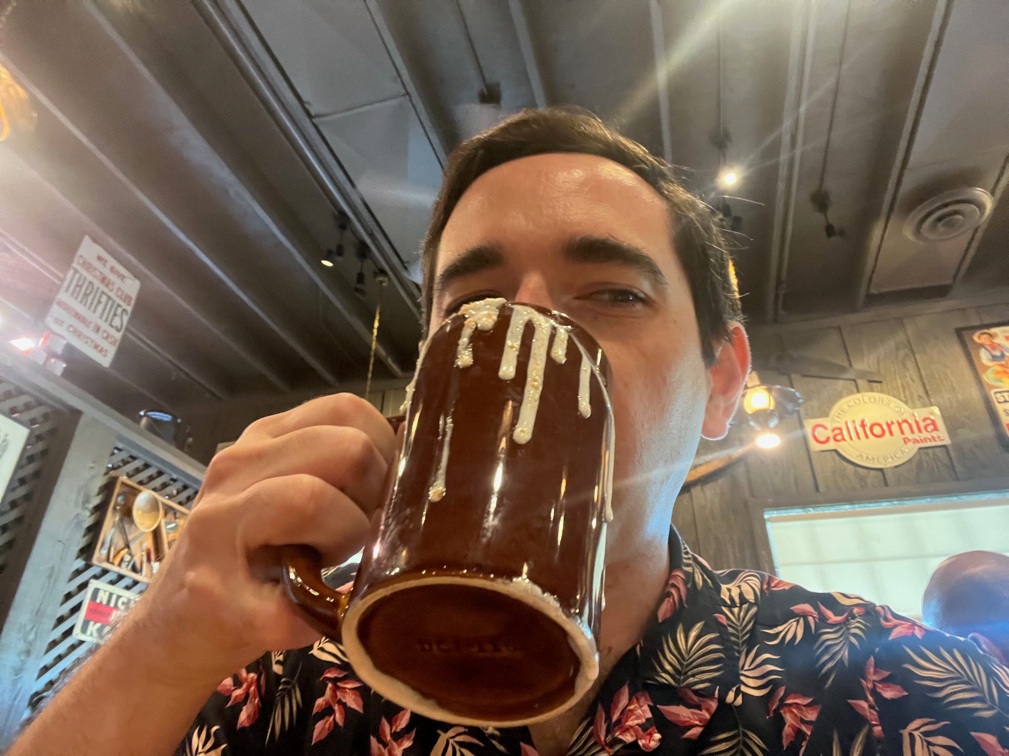 The author drinks a latte at a Cracker Barrel restaurant with antique signs in the background.