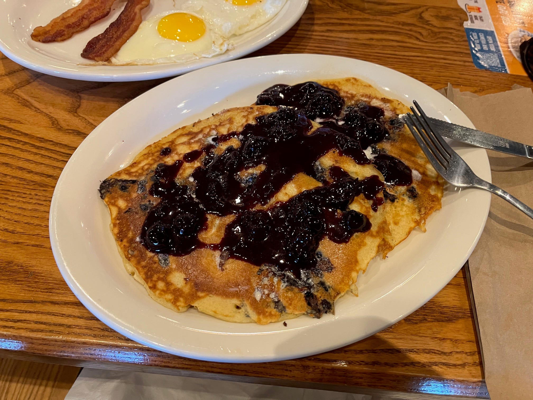 Blueberry pancakes with syrup sit on a plate at Cracker Barrel