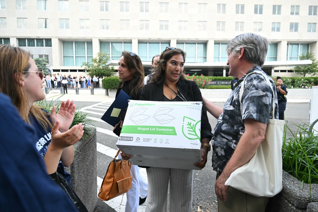 A laid-off State Department employee is comforted by a supporter outside the Harry S. Truman building in Washington, D.C.