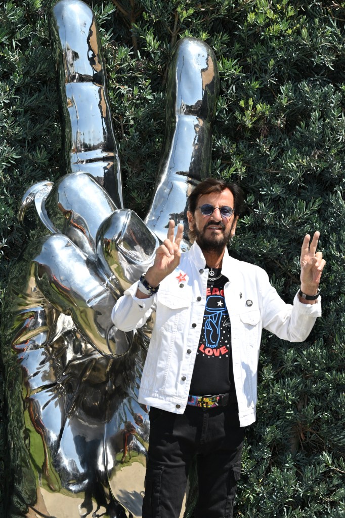 Beatles great Ringo Starr flashes the peace sign in front of a “Peace and Love” sculpture he designed and donated in Beverly Hills.