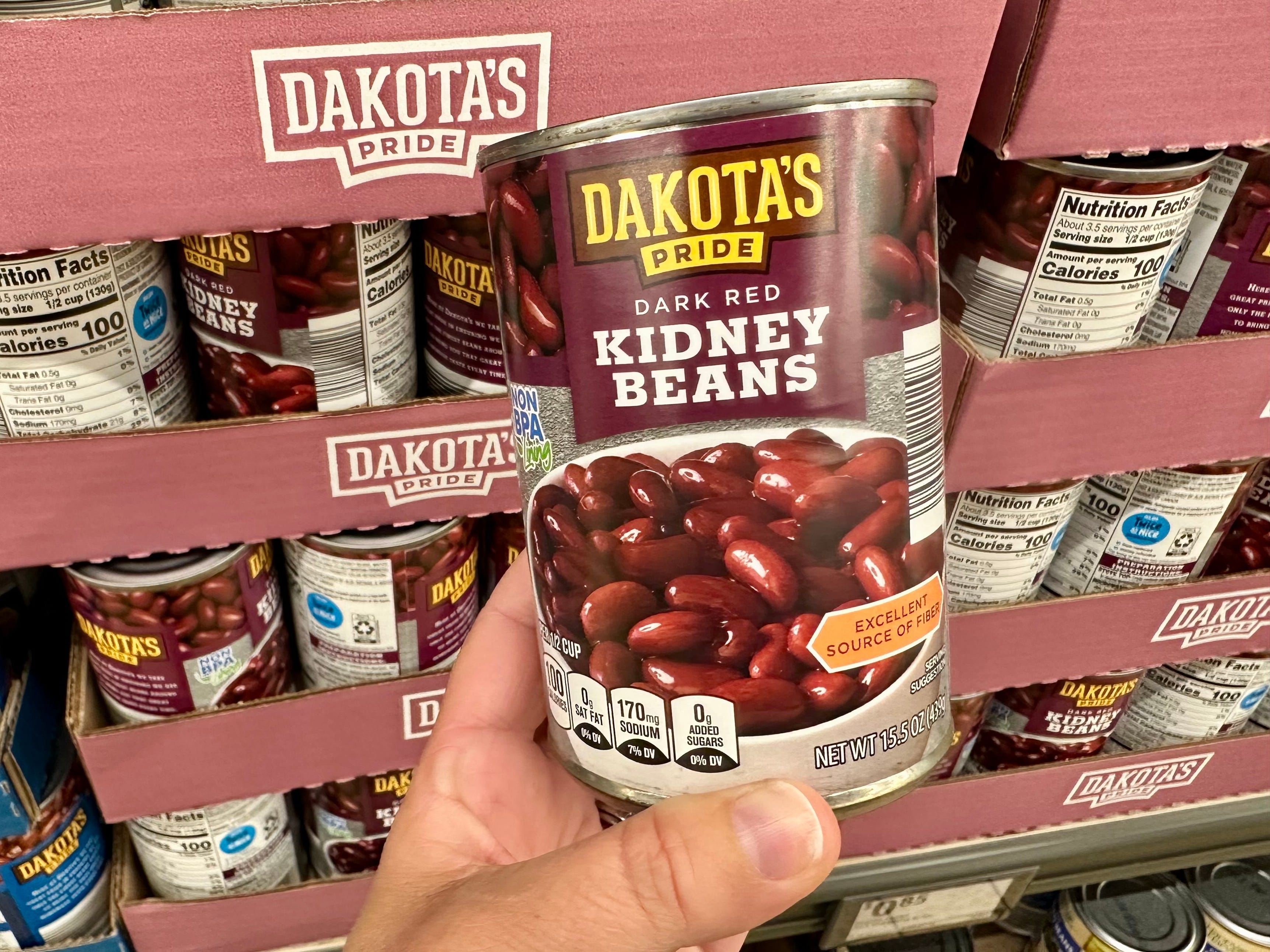 A hand holding a can of Dakota's Pride dark red kidney beans.