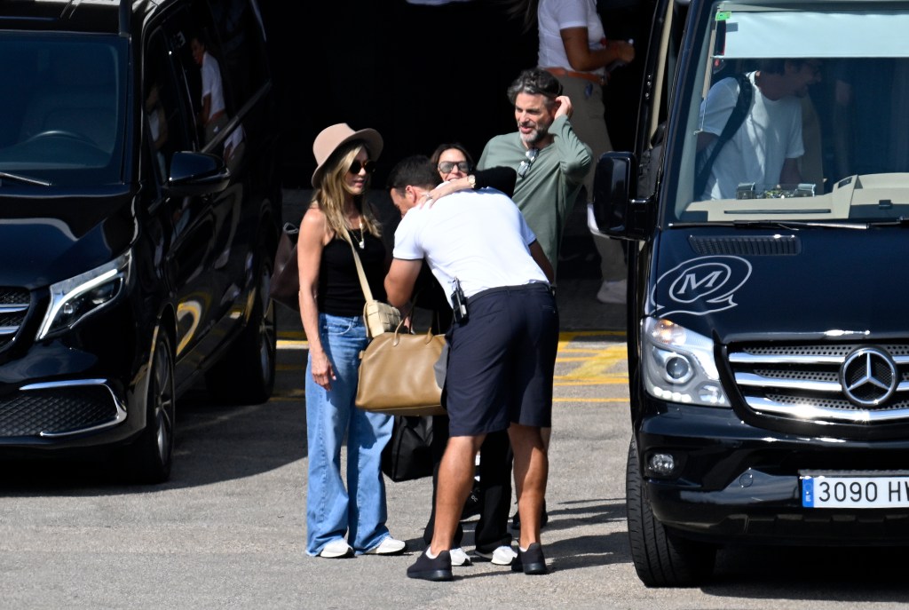 Jennifer Aniston in a black tank top, jeans, and a straw hat, Jim Curtis in a khaki t-shirt.