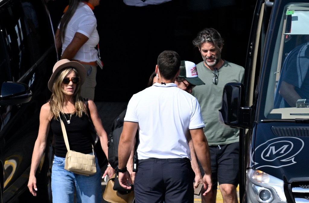 Jennifer Aniston in a black tank top, jeans, and a straw hat, Jim Curtis in a khaki t-shirt.