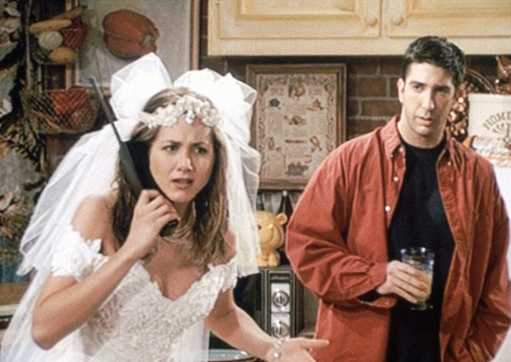 Jennifer Aniston in a wedding dress and veil, David Schwimmer in a red shirt and black t-shirt.