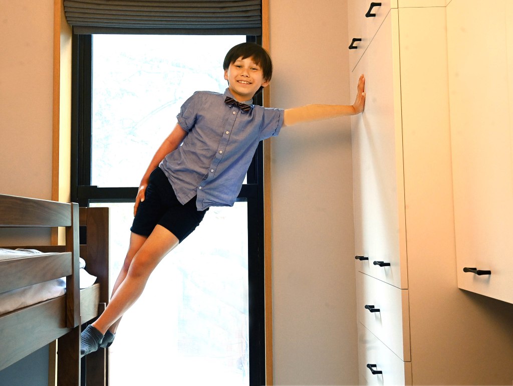 Julian Lin smiling and leaning from his bunk bed to hold onto the closet door in his family's Upper West Side apartment