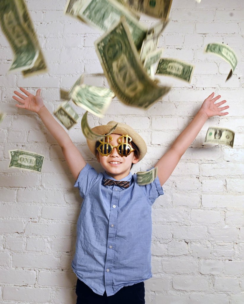 Julian Lin wearing dollar-sign shaped sunglasses and throwing money in the air