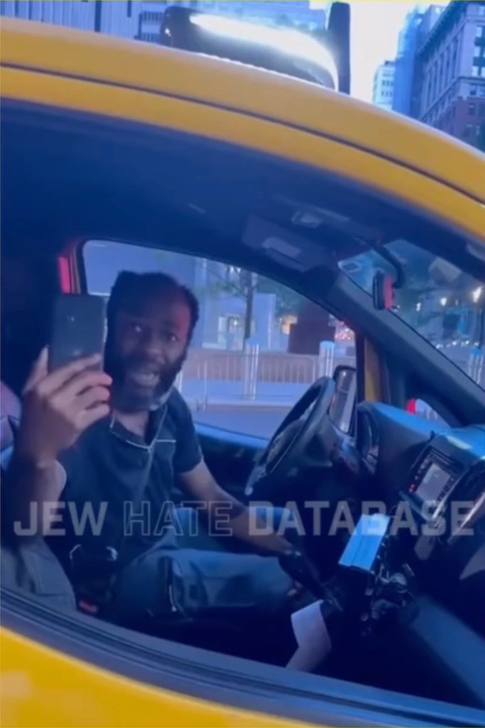 the cabbie holding up a cell phone and talking to someone at the window of the vehicle