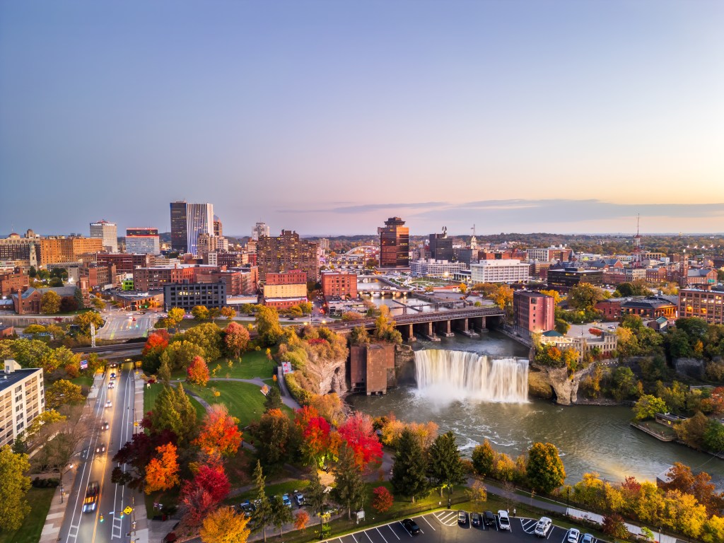 Aerial view of Rochester, New York at dusk, showing the city skyline and High Falls.