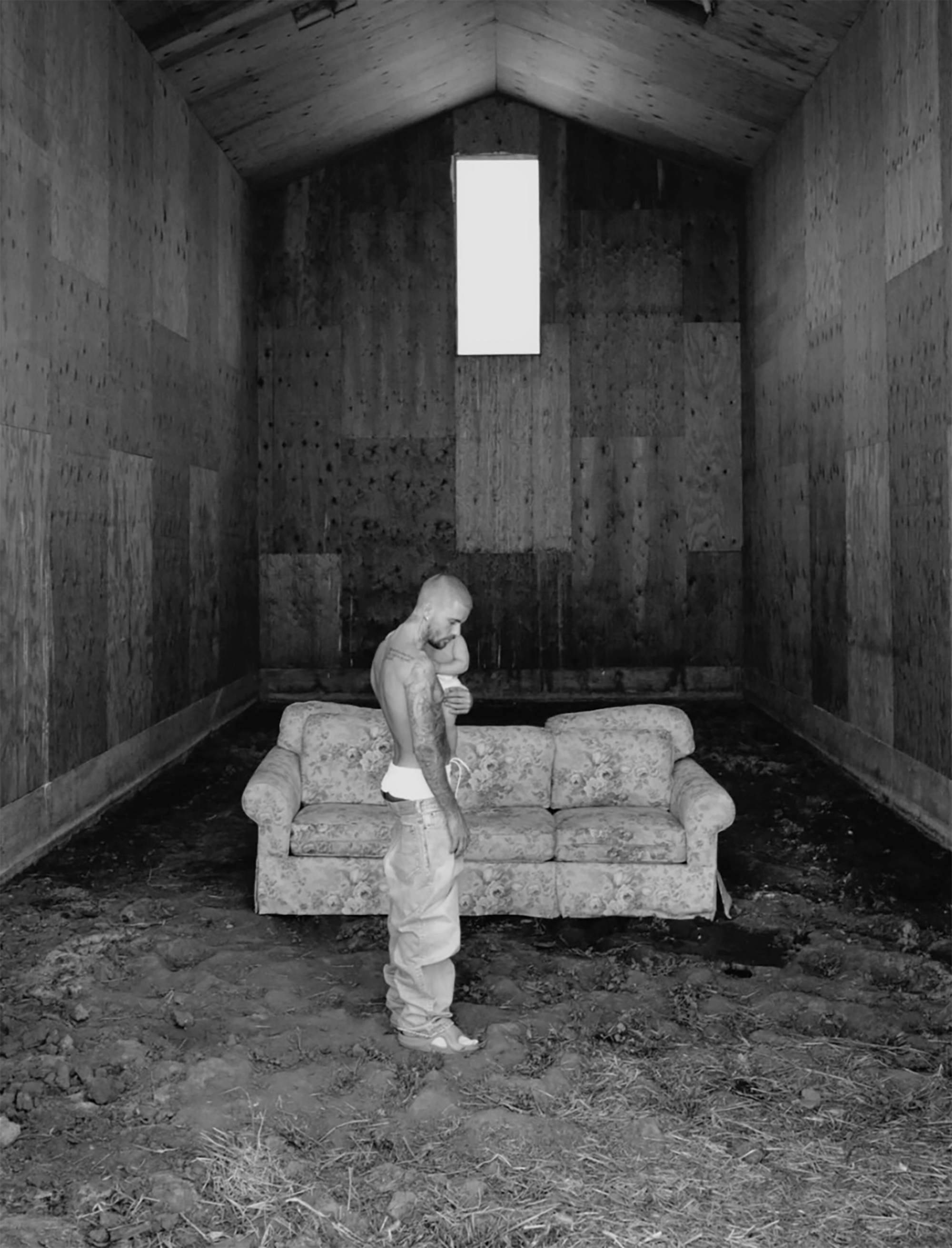 Justin Bieber in a black and white photo by a couch. 