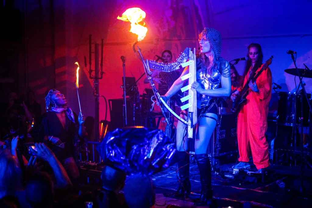 A woman plays a fire harp during a brass band performance.