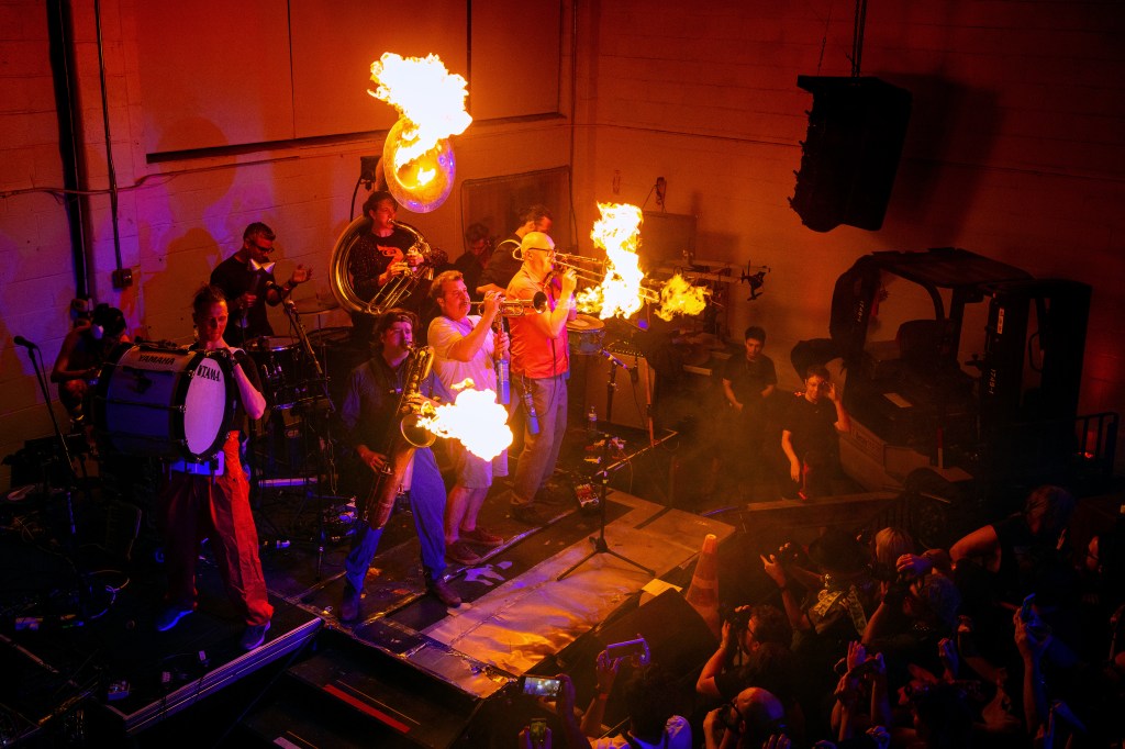 Brass band performing with fire on their instruments.