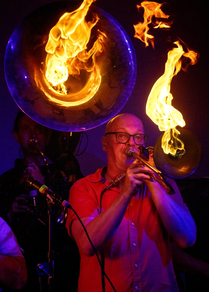 Trombonist playing with fire during a performance.
