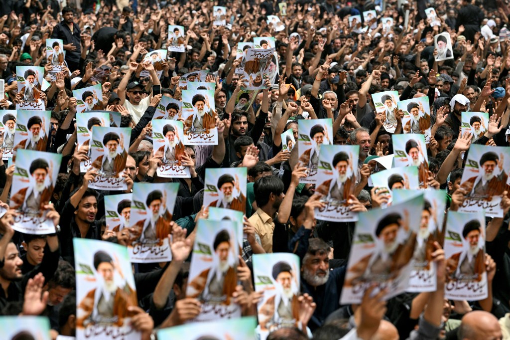 Mourners at an Ashura procession in Karachi holding portraits of Ayatollah Ali Khamenei.