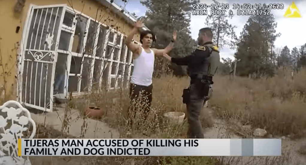 Screenshot of a man in handcuffs being apprehended by a police officer.