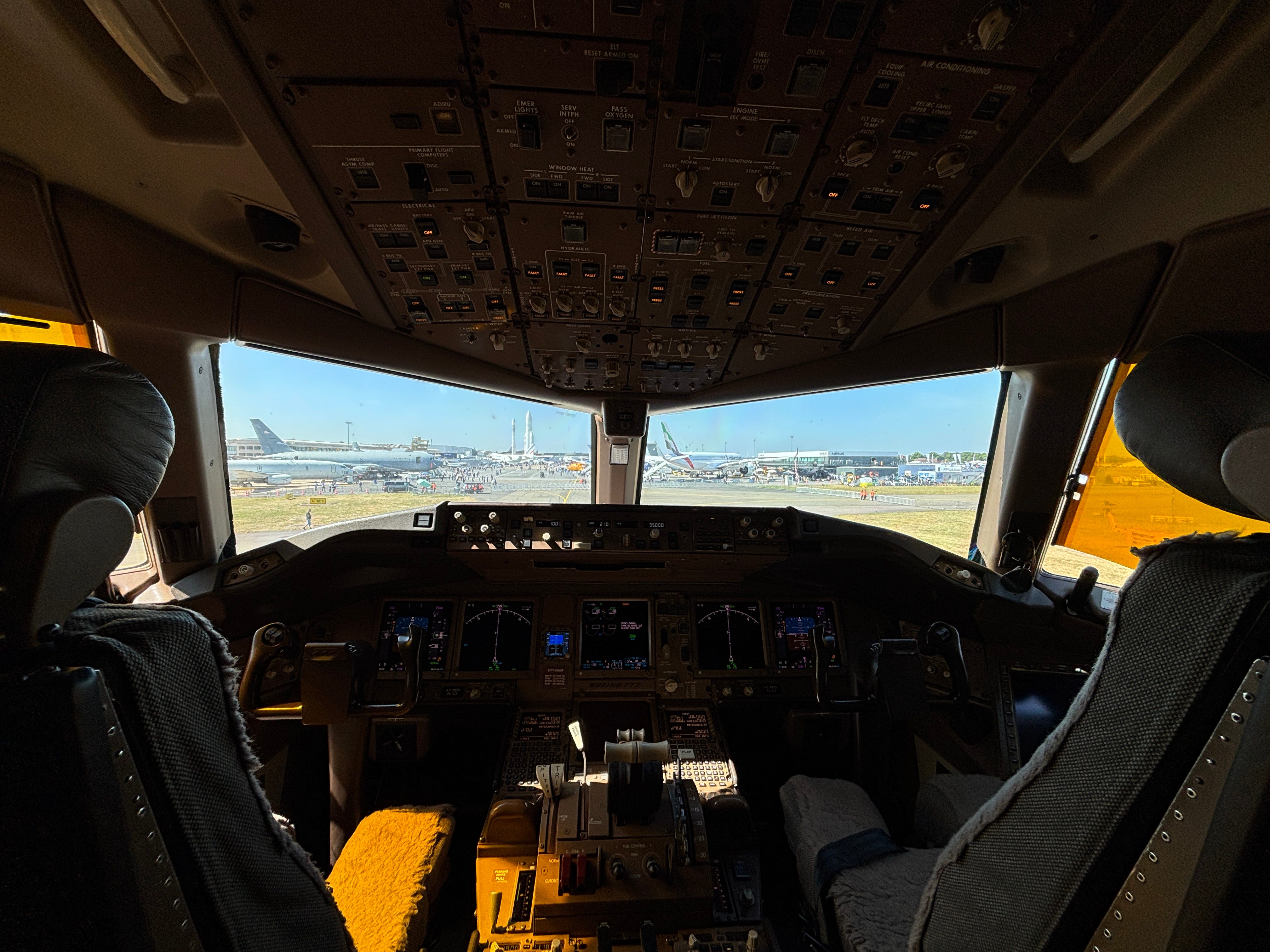 The flight deck of a Qatar Airways Boeing 777 with a view of the 2025 Paris Air Show through the windscreen