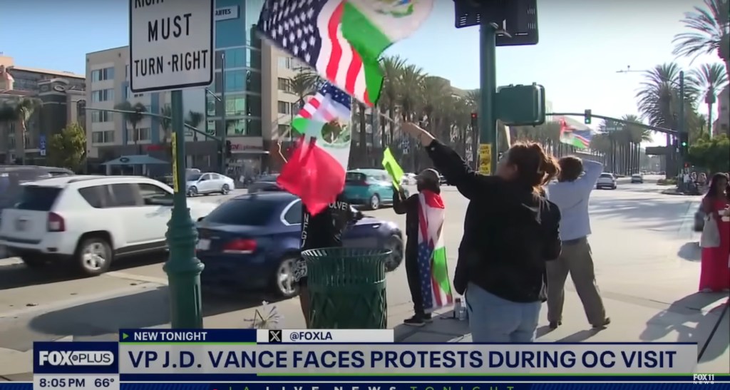 Protestors holding flags outside Disneyland during VP Vance's visit.