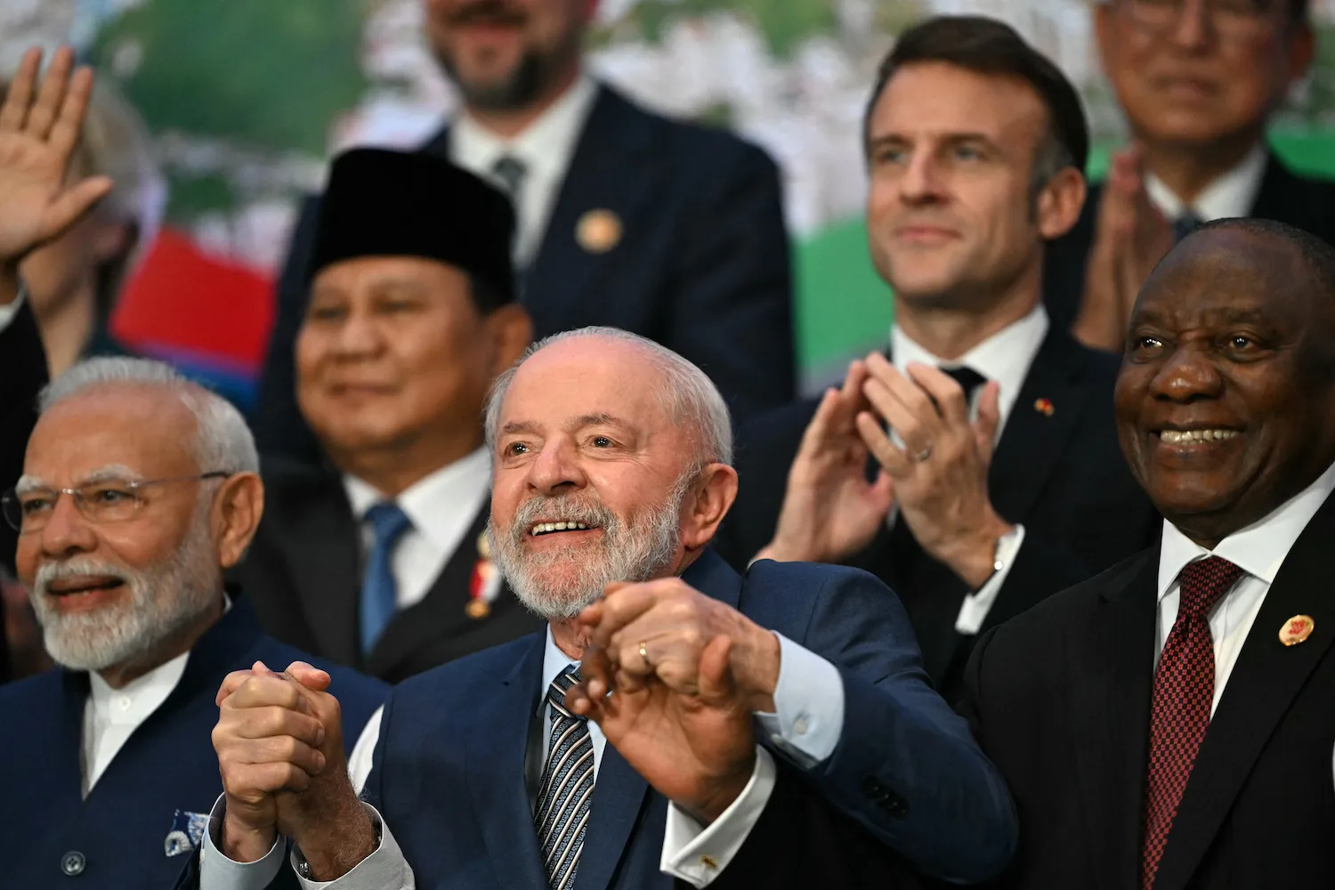 Leaders hold hands as they pose for the camera.
