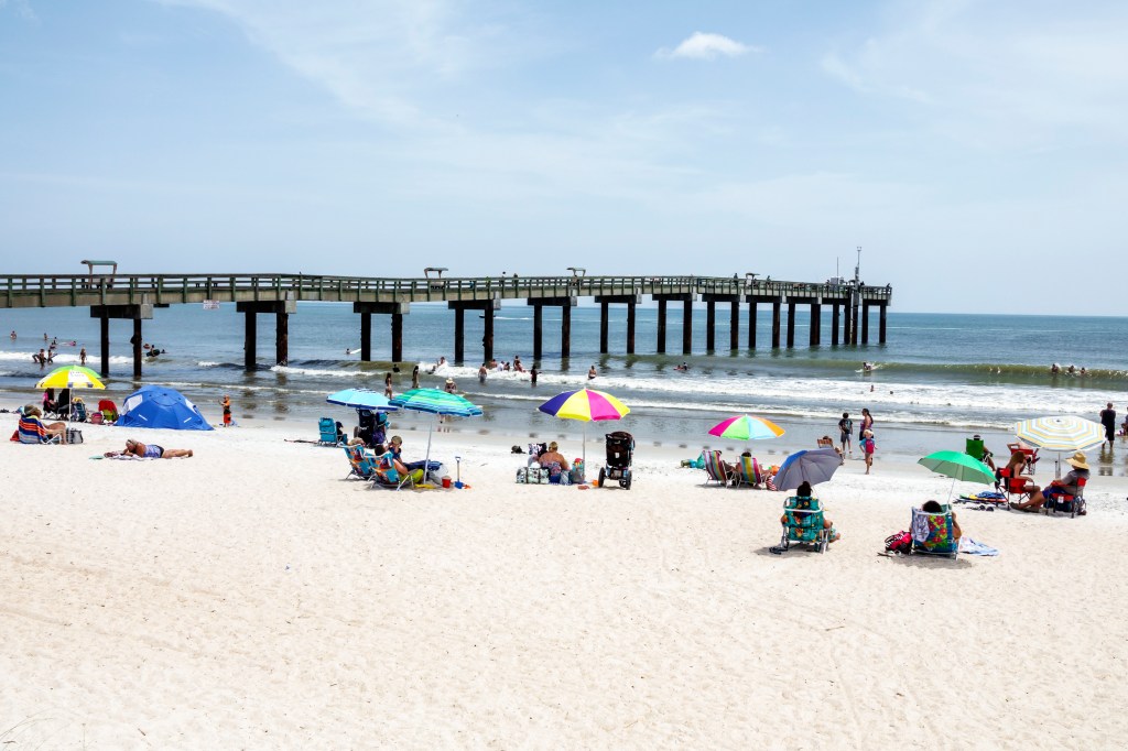 St. Augustine Beach pier with sunbathers relaxing on the sand.