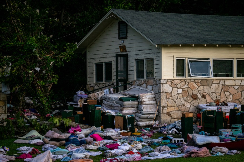 Photo of belongings strewn across the lawn outside a flood-damaged building.