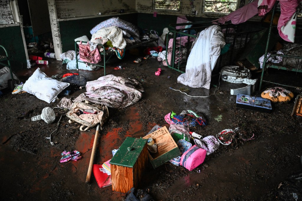 Muddy interior of a cabin after a flood, with belongings scattered on the floor.