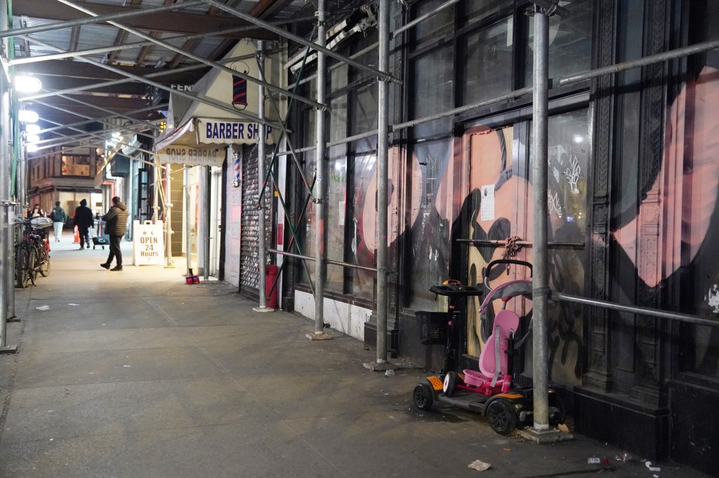 Scaffolding in front of New York City storefronts at night.