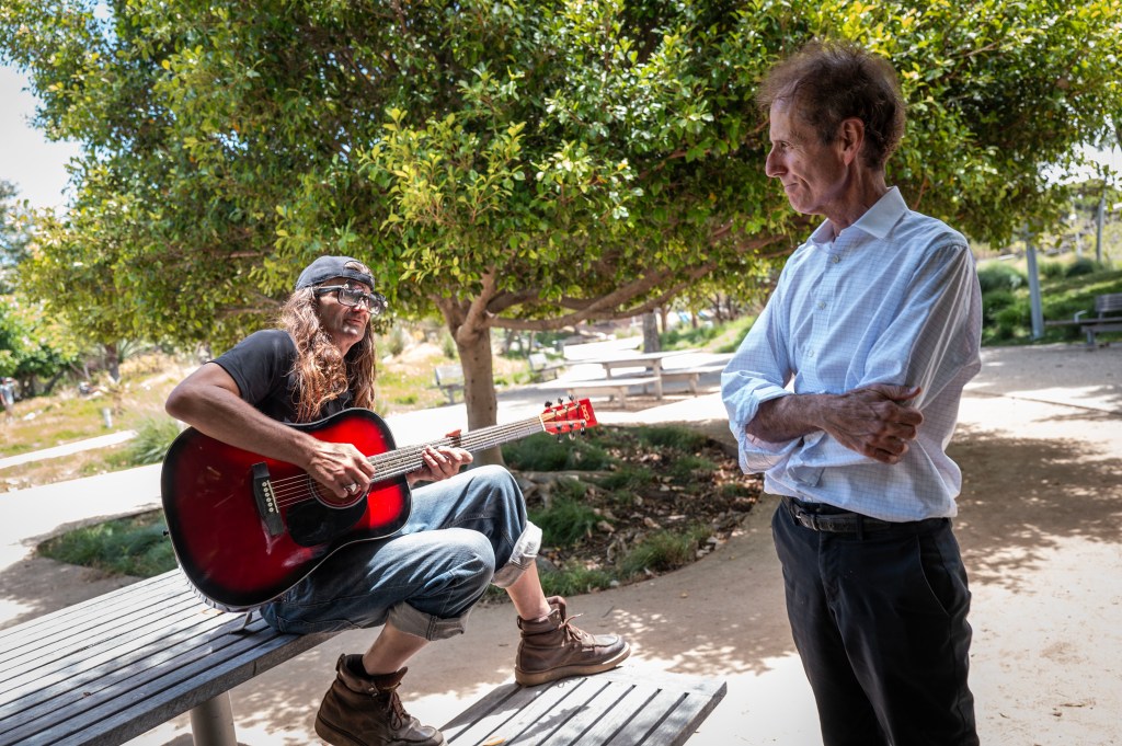 John Alle speaks to a homeless man from Alabama in a Santa Monica park.