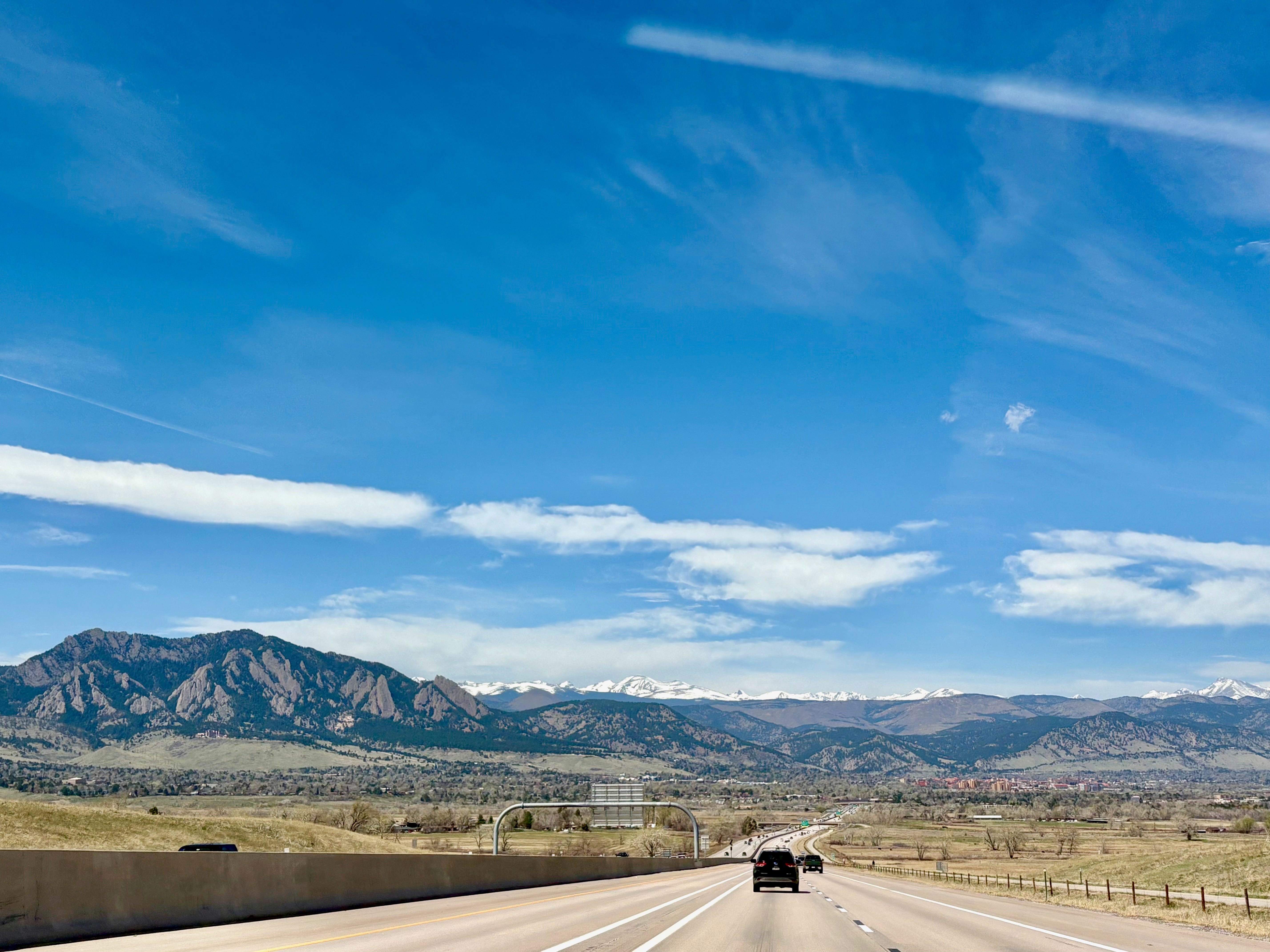 The author's view of snow-capped mountains in the distance while on a highway in Colorado.