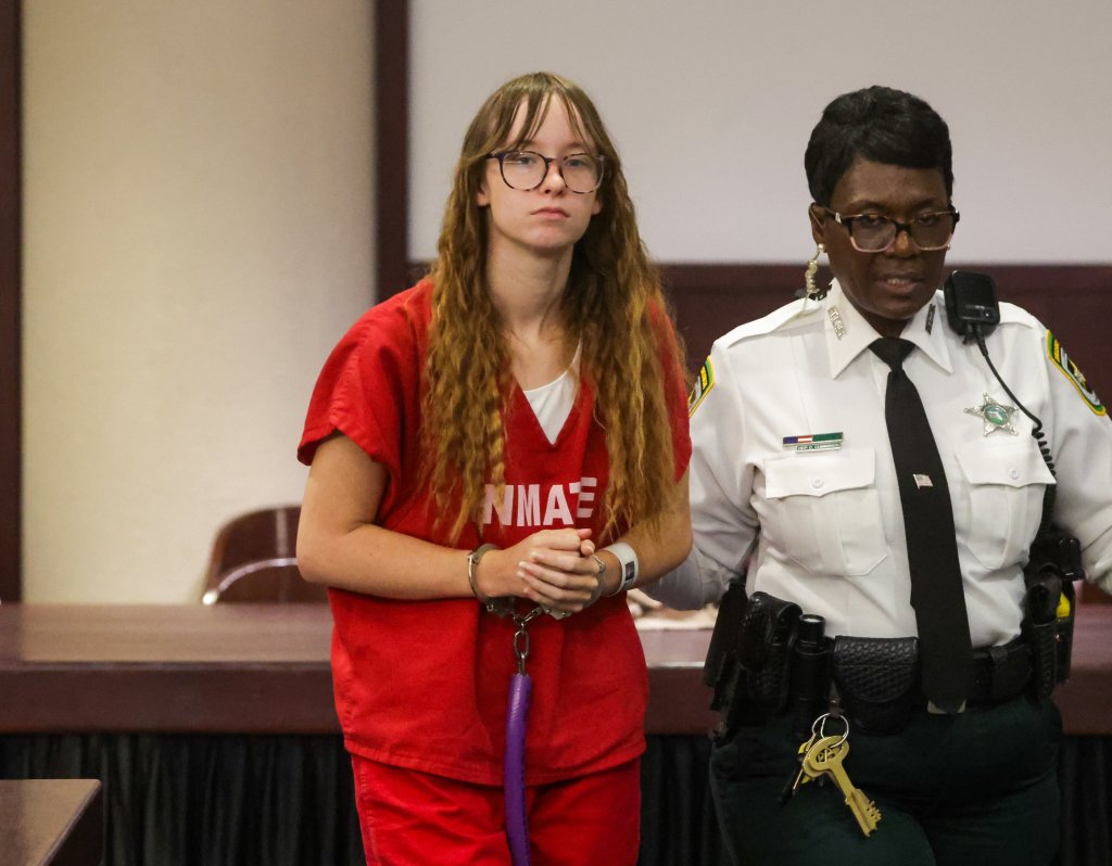 Brianna Moore, handcuffed and in an orange jumpsuit, escorted by a sheriff's deputy.