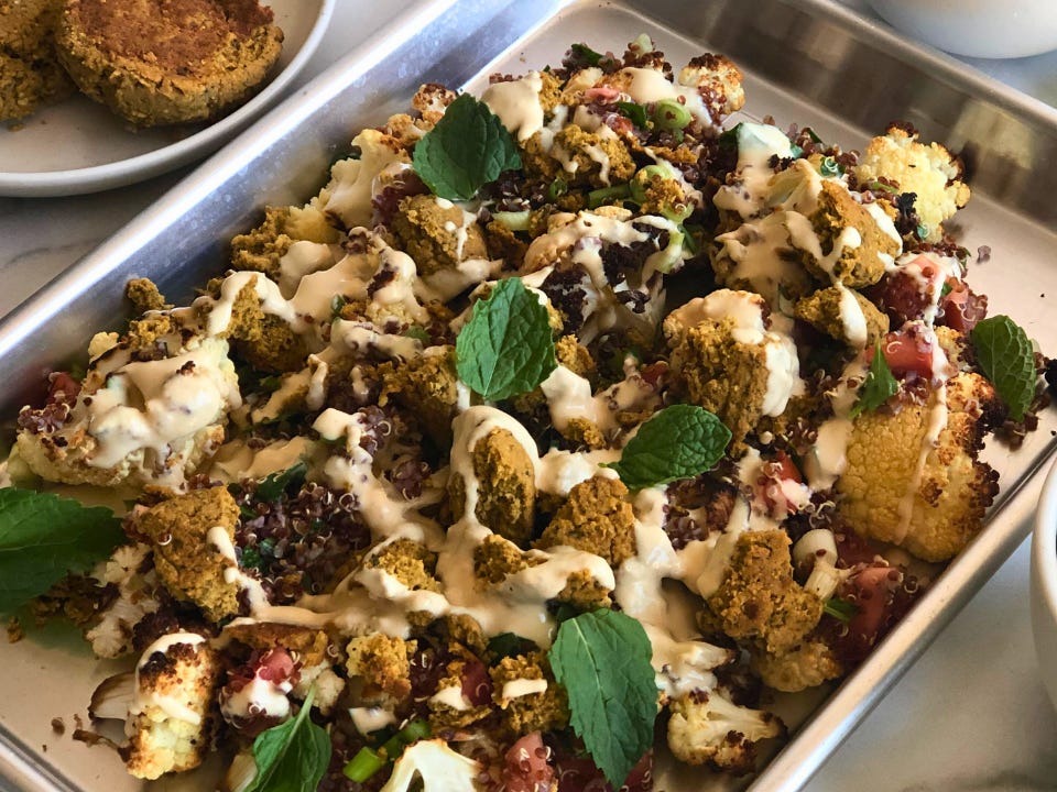 Roasted cauliflower and falafel on a sheet pan, topped with tabbouleh and drizzled with hummus.