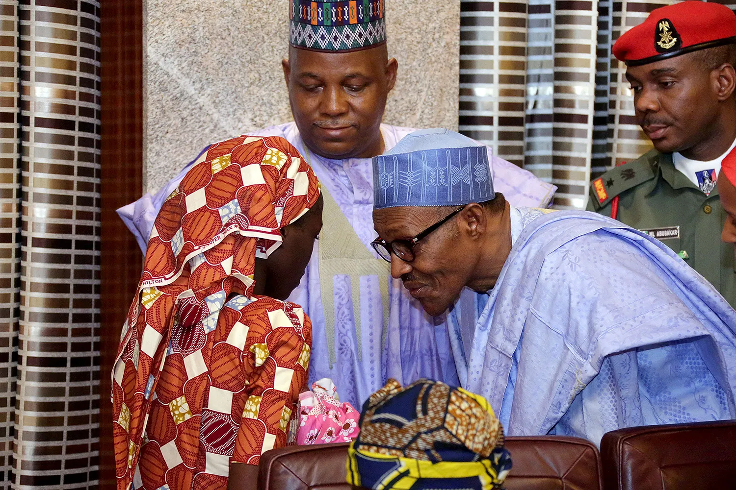 Muhammadu Buhari bends down to speak with a young girl.